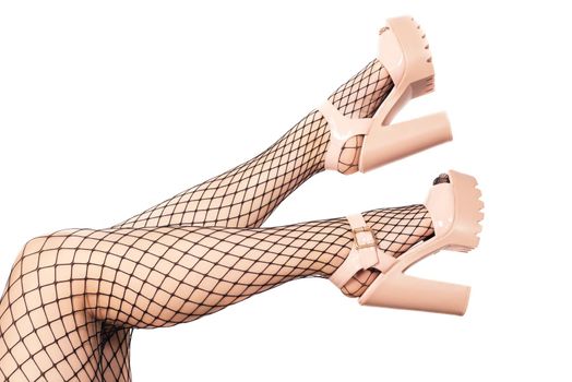 Sexy female legs in net stockings and sandals with high heels isolated over white.