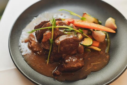 Beef Bourguignon in a black plate