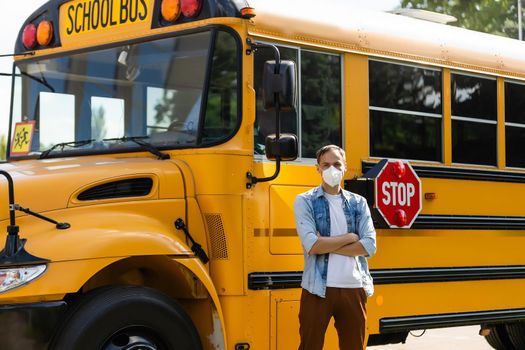 masked teacher near the school bus