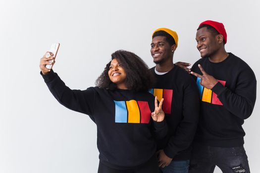 Friendship and fun concept - Group of friends afro american men and woman taking selfie in studio on white background