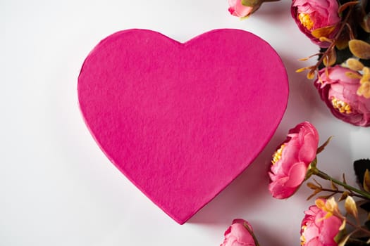 Pink heart for valentines day on a background of flowers. Heart shaped greeting card on pink flowers background