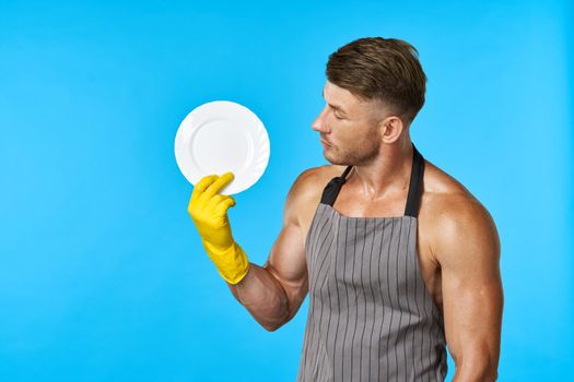 Dishwasher rubber gloves plate in hands blue background. High quality photo