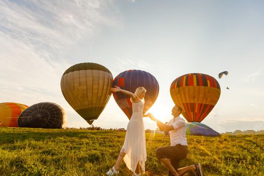 Beautiful romantic couple hugging at meadow. hot air balloon on a background