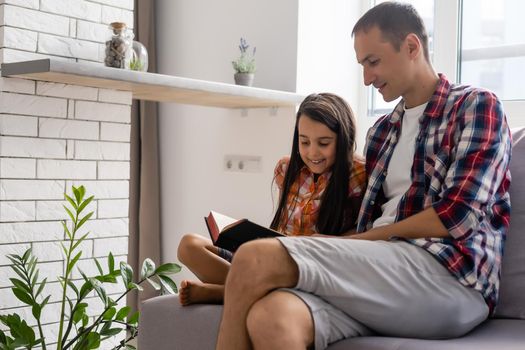 Father reading Bible to his little child daughter at home