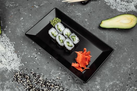 Delicious, juicy and mouth-watering maki with cucumber. Sushi on a gray background.