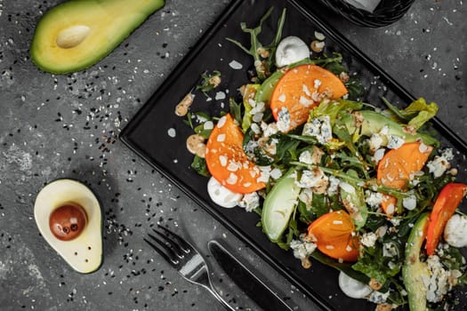 Fresh salad with fruits and greens on dark canvas background. Healthy food.