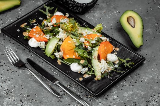 Fresh salad with fruits and greens on dark canvas background. Healthy food.