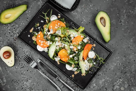 Fresh salad with fruits and greens on dark canvas background. Healthy food.