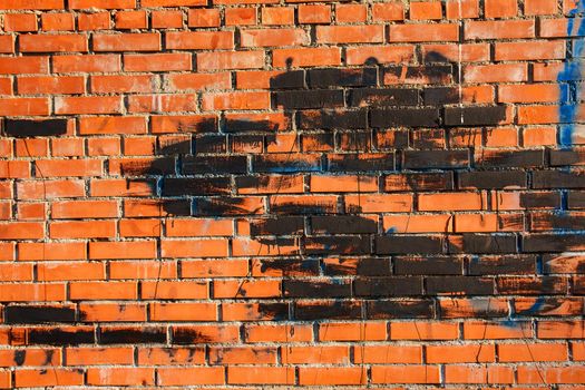 old brick wall with spots of paint of blue and black color.