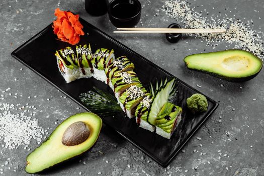 Green dragon sushi roll with eel, avocado, cucumber and ginger, accompanied with fried tempura shrimp. Traditional asian rice sushi healthy seafood.