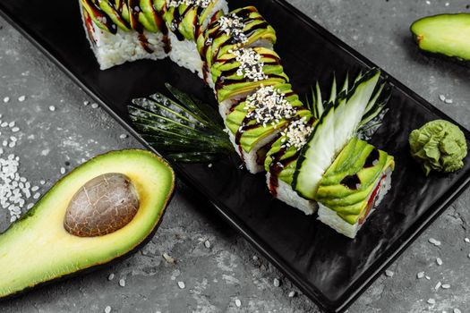 Green dragon sushi roll with eel, avocado, cucumber and ginger, accompanied with fried tempura shrimp. Traditional asian rice sushi healthy seafood.