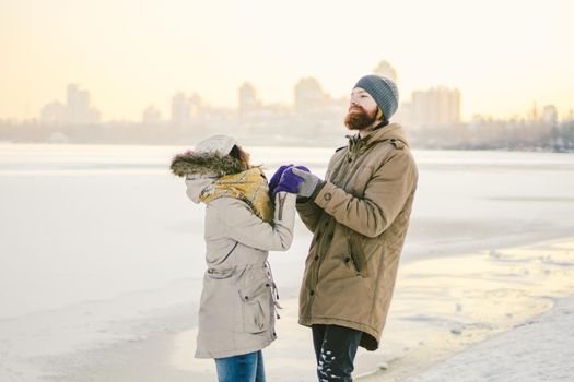 Young couple cheerfully flounders in snow. Between comic fight. Happy young couple hugs in winter snowy woods. Romantic lifestyle men and women in love. St. Valentine Day date Christmas hugging happy.