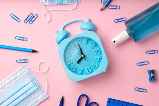 Blue alarm clock and medical face mask, top view