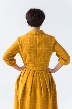 clothing, designer, people concept - back view of attractive woman in a yellow dress posing on white room