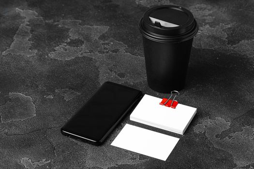 Mock up of blank business card and black smartphone screen on table, close up