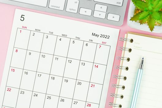 The May 2022 calendar sheet with keyboard computer on pink background.
