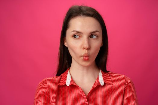 Portrait of pretty young woman sucked in her cheeks against pink background, close up