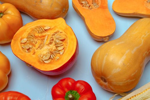 Variety of vegetables including pumpkins on blue pastel background top view