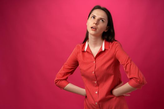 Tired and bored young woman portrait against pink studio background, close up