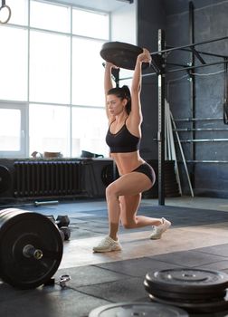 Close up front portriat of a woman is lifting weight while working out in gym. Sport and healthy lifestyle concept.