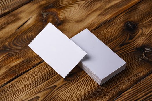 Stack of white business cards on brown wooden background, close up