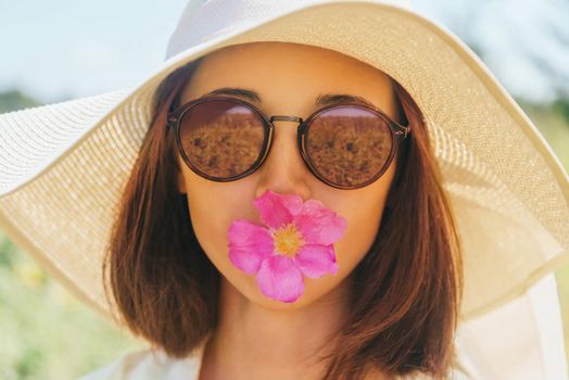 Portrait of beautiful woman in sunglasses and hat with wide brim with flower, concept of happiness and summer mood