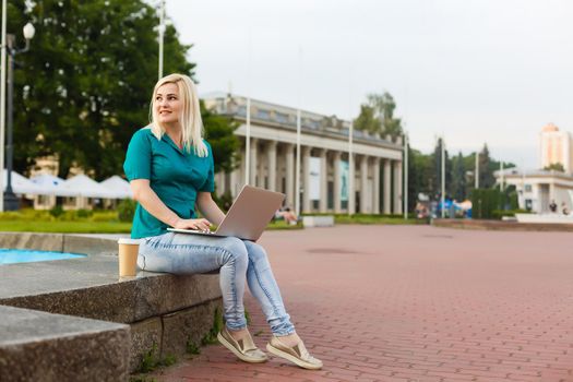 woman searching job with a laptop in an urban park in summer