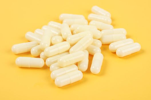 Yellow pharmaceutical medicine capsules over yellow background.