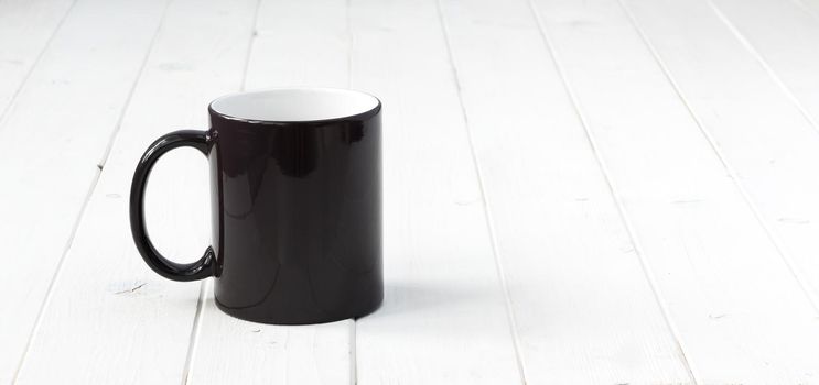 black cup with white inside on planked wooden table