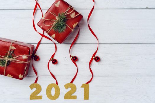 Packed small Christmas gifts and red baubles on white wooden board top view