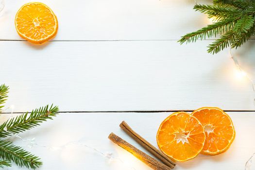 Slices of dried oranges, cinnamon sticks, fir branches. tinsel and gold garland on a white wooden background. Christmas, new year, holiday, warm autumn and winter atmosphere. Copy space, flat lay
