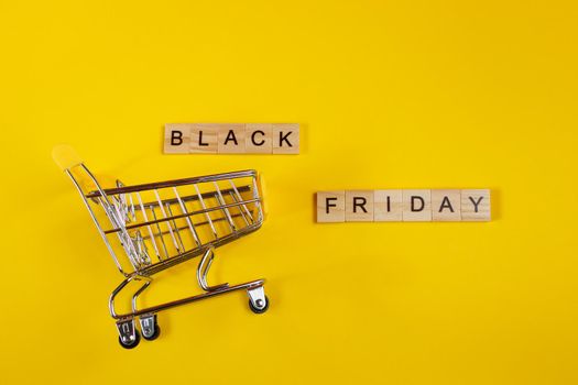 Sale and Black Friday concept. Mini shopping cart on a yellow background.