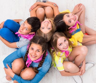 teenagers sitting on the floor smiling at camera, top view
