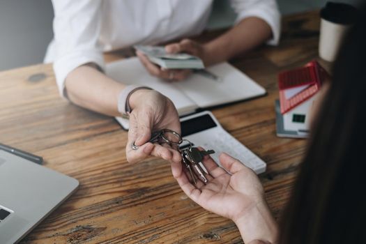 Close up of Business woman giving house key after signing agreement for buying house. Bank manager and real estate concept