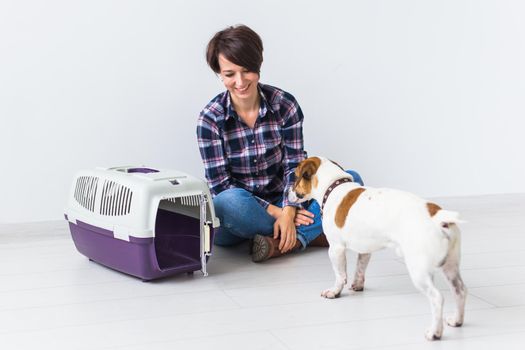 Dog carrying bags and pets owner concept - Attractive cheerful female in plaid shirt holds favourite pet. Happy woman with her jack russell terrier.