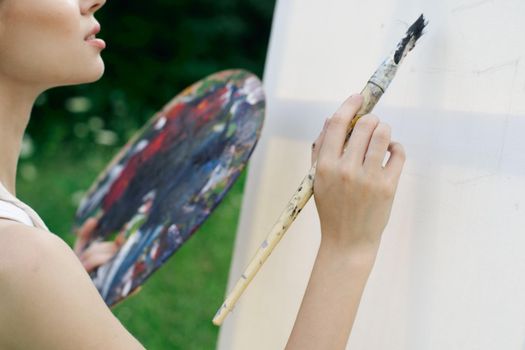 woman artist paints palette easel nature drawing. High quality photo