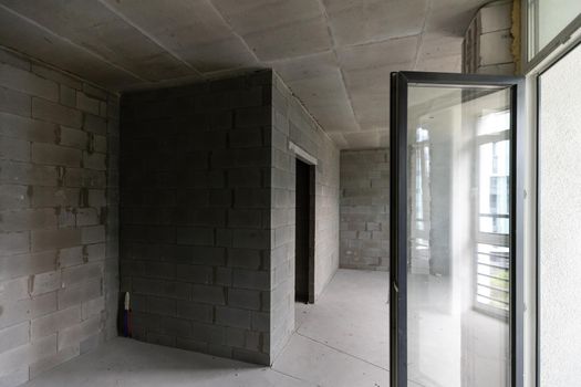A new unfinished apartment room with the bare brick walls without decoration.