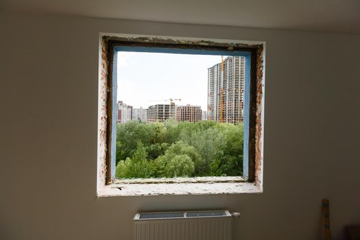 Empty frame on a wide panoramic window. Gorgeous view from the window of an apartment in a multi-storey building. Roofs of houses and trees from a height. Beautiful view through the window. Frame for
