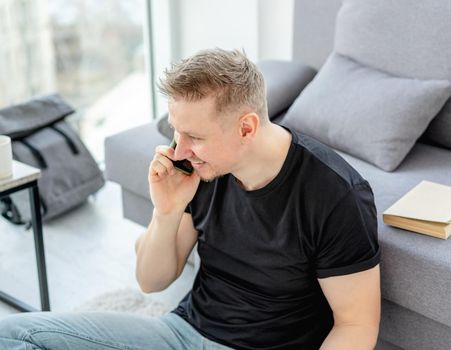 Happy man talking on phone in light apartment