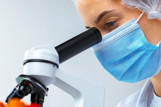 Woman scientist looking through a microscope in laboratory. Scientific research