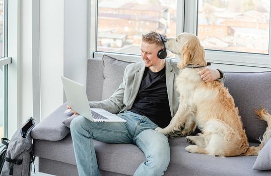 Businessman teleworking on laptop next to cute dog