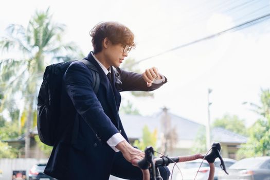 Handsome young asian businessman in suit have smiling with bicycle go to work at morning.