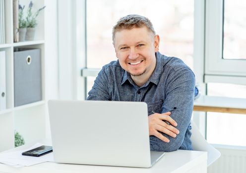 Beautiful man with headphones and laptop at work