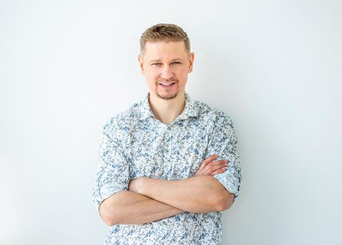 Attractive man with crossed hands on light wall background