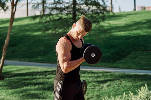 pumped up sports Vykhino in the park with dumbbell workout. High quality photo