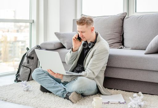 Smiling man working on laptop and phone at home