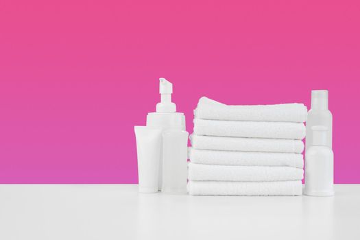 Pile of towels, bottles with shampoo on white table isolated