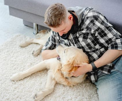 Handsome man with cute dog in light room