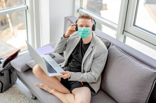 Man in medical mask working at home during covid pandemic