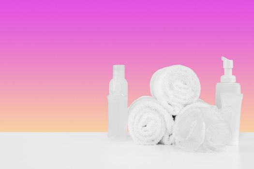 Pile of towels, bottles with shampoo on white table isolated